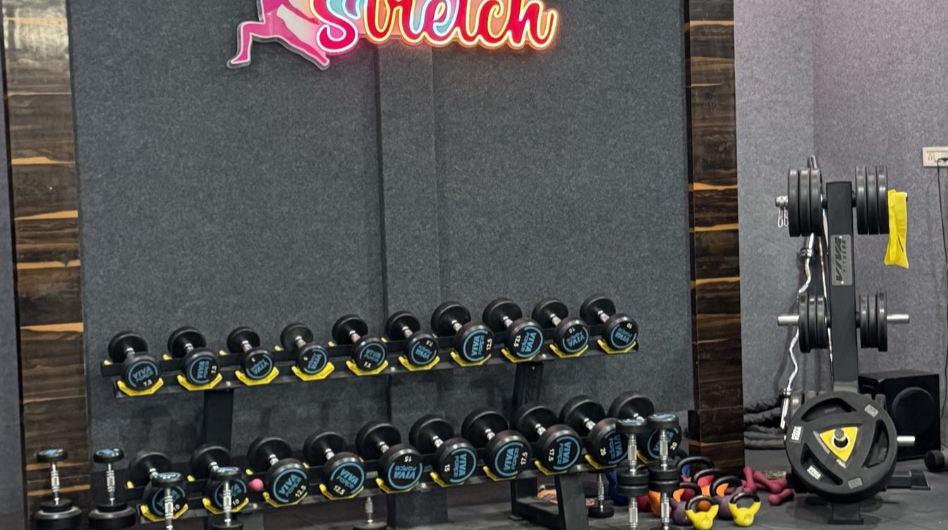 Dumbbell rack and weight plates below the Moves n Stretch studio sign